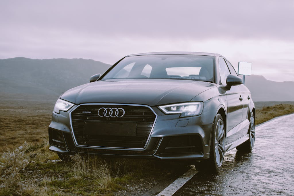 Elegant grey Audi sedan parked roadside, showcasing luxury automotive design against a scenic backdrop.