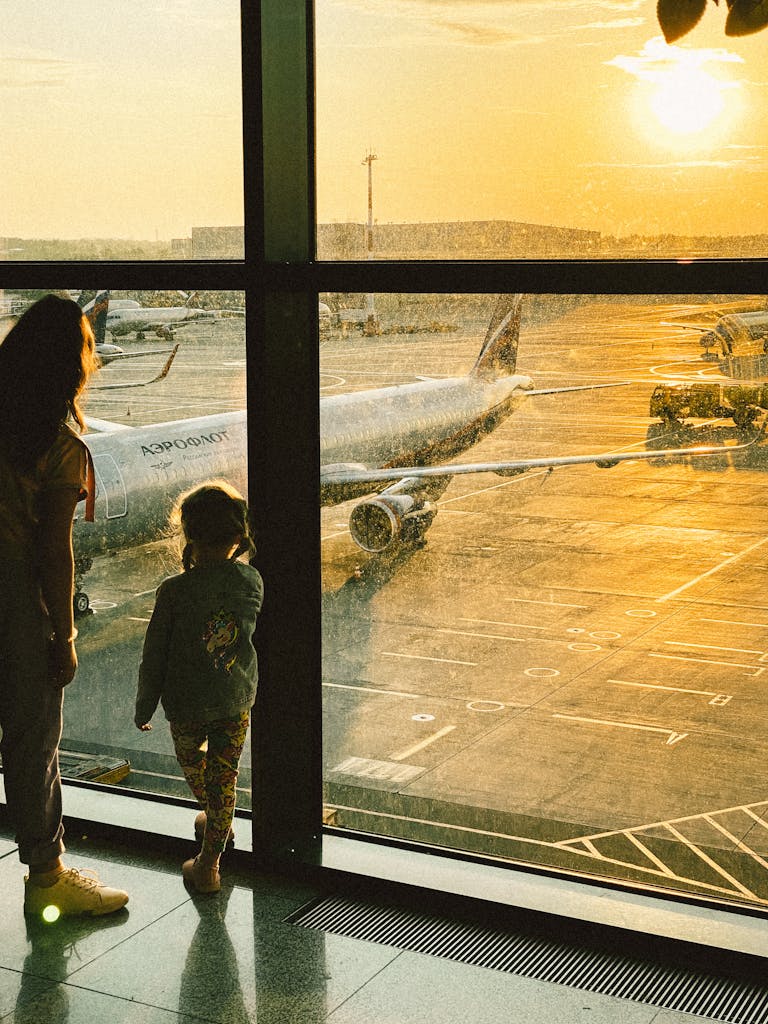 A mother and daughter watch planes at Moscow airport during sunrise. Travel concept.