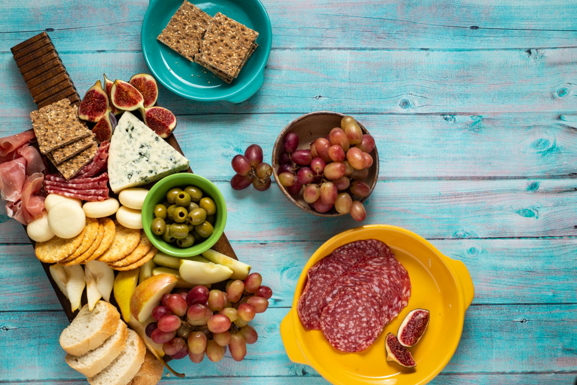 Gorgonzola Cheese On A Wooden Cheese Board With Blue-green Veins Visible, Accompanied By Crackers And Fruits
