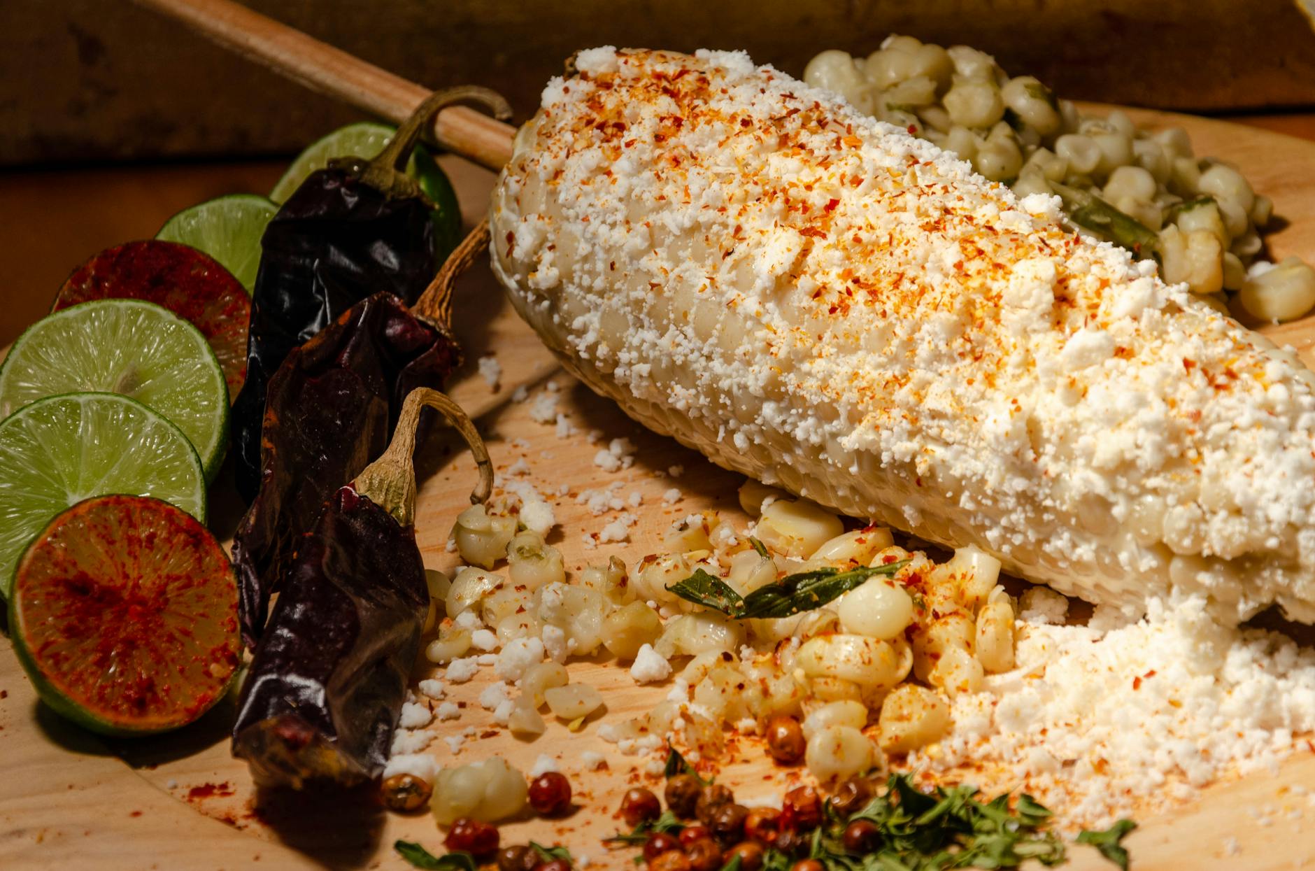 Cotija Cheese On A Rustic Wooden Table With Tacos And Elote Corn In The Background