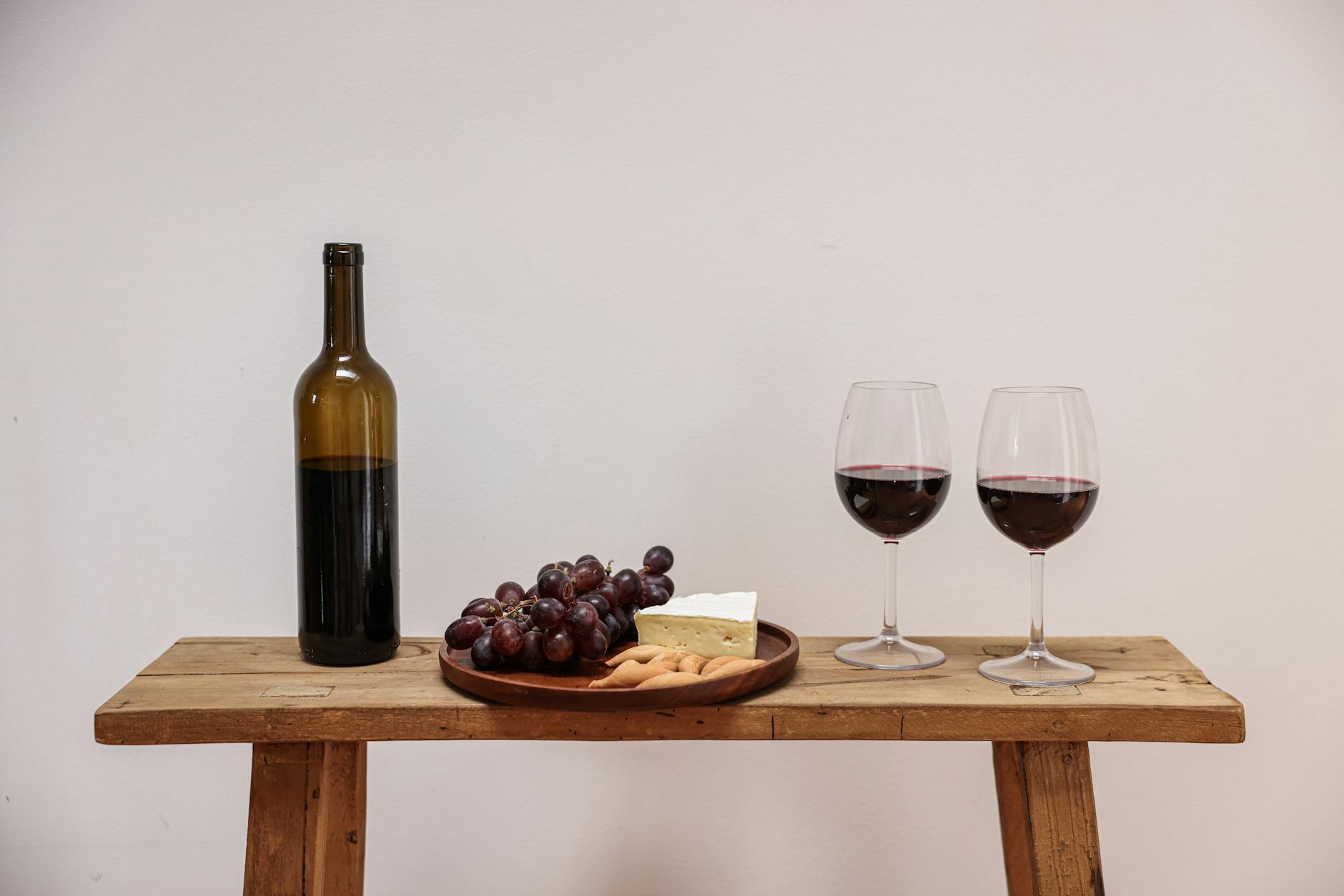 Taleggio Cheese On A Wooden Cheese Board With A Glass Of Red Wine And Grapes