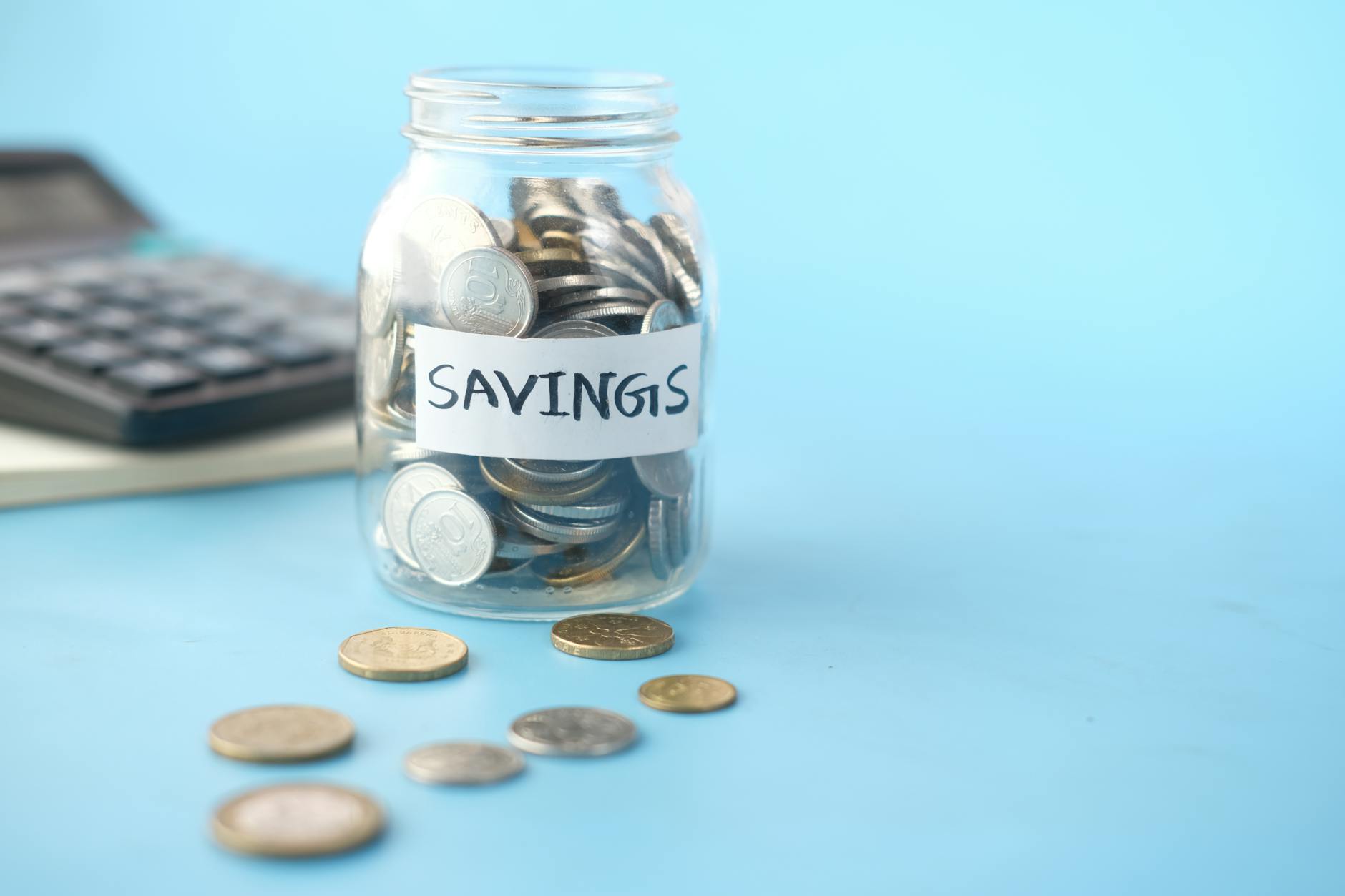 Emergency Fund Savings Jar With Cash And Coins, Financial Documents, And A Calculator On A Wooden Table