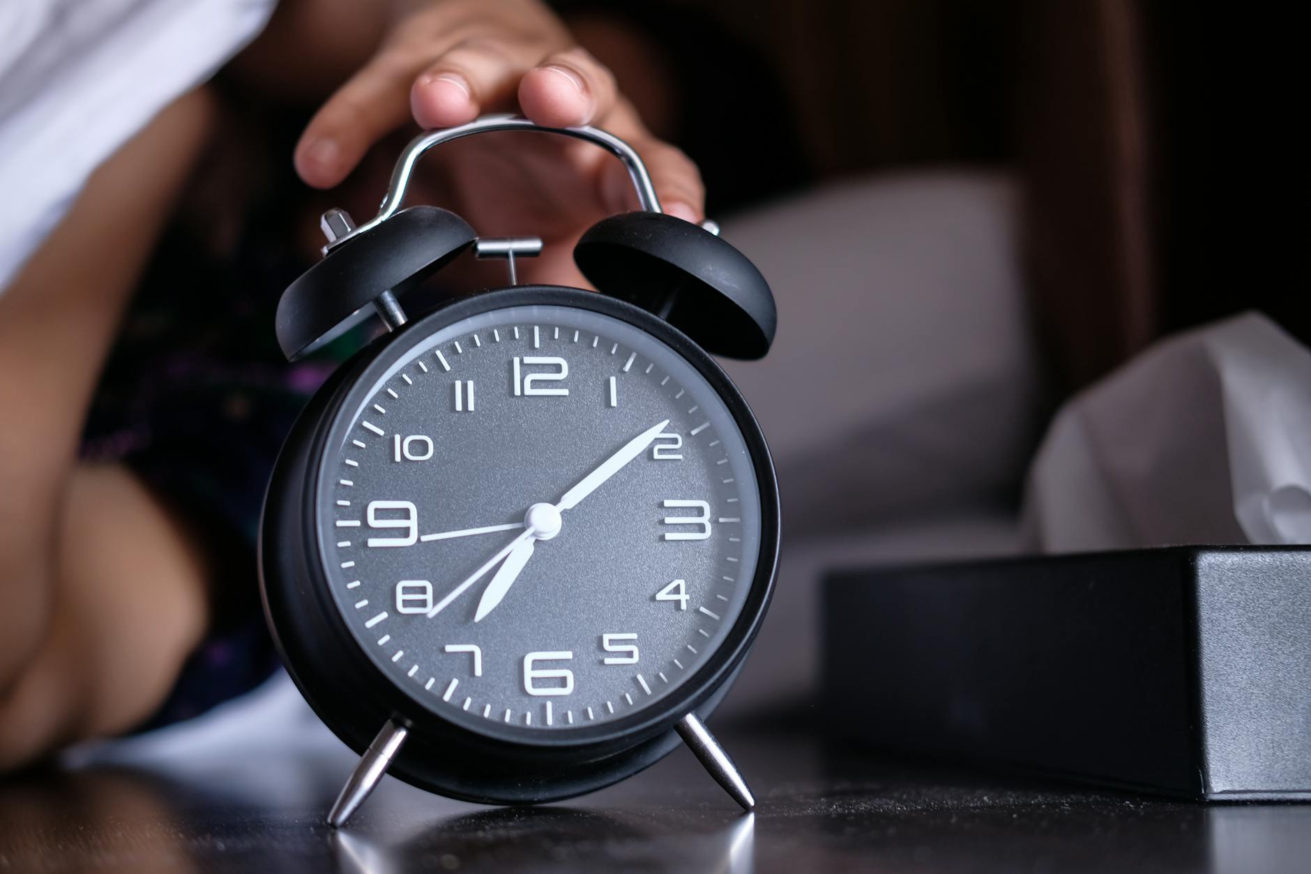 Person Hitting Snooze Button On Alarm Clock