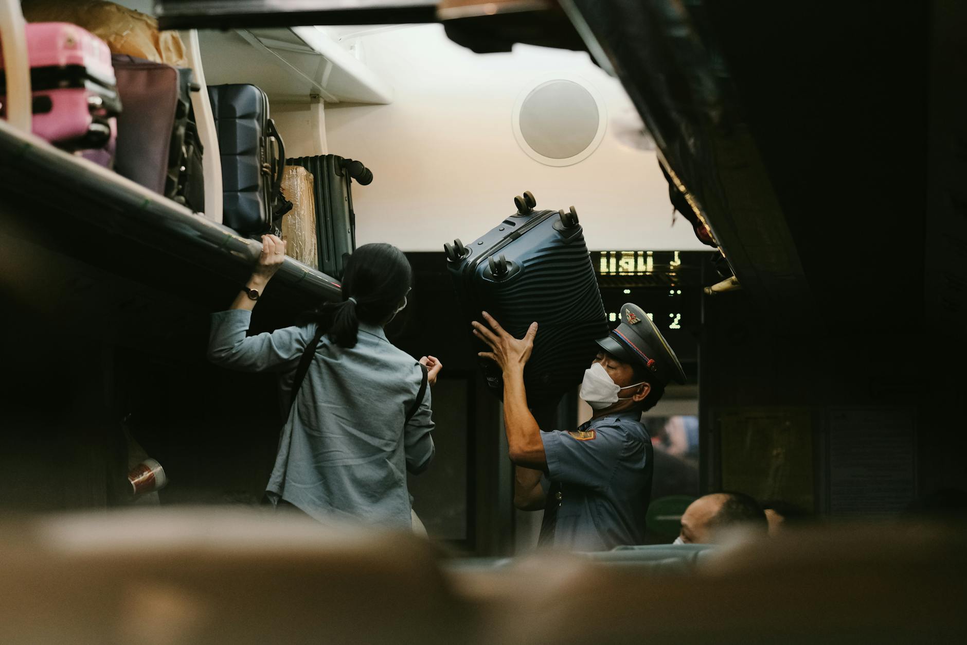 Flight Attendant Assisting Passenger With Luggage