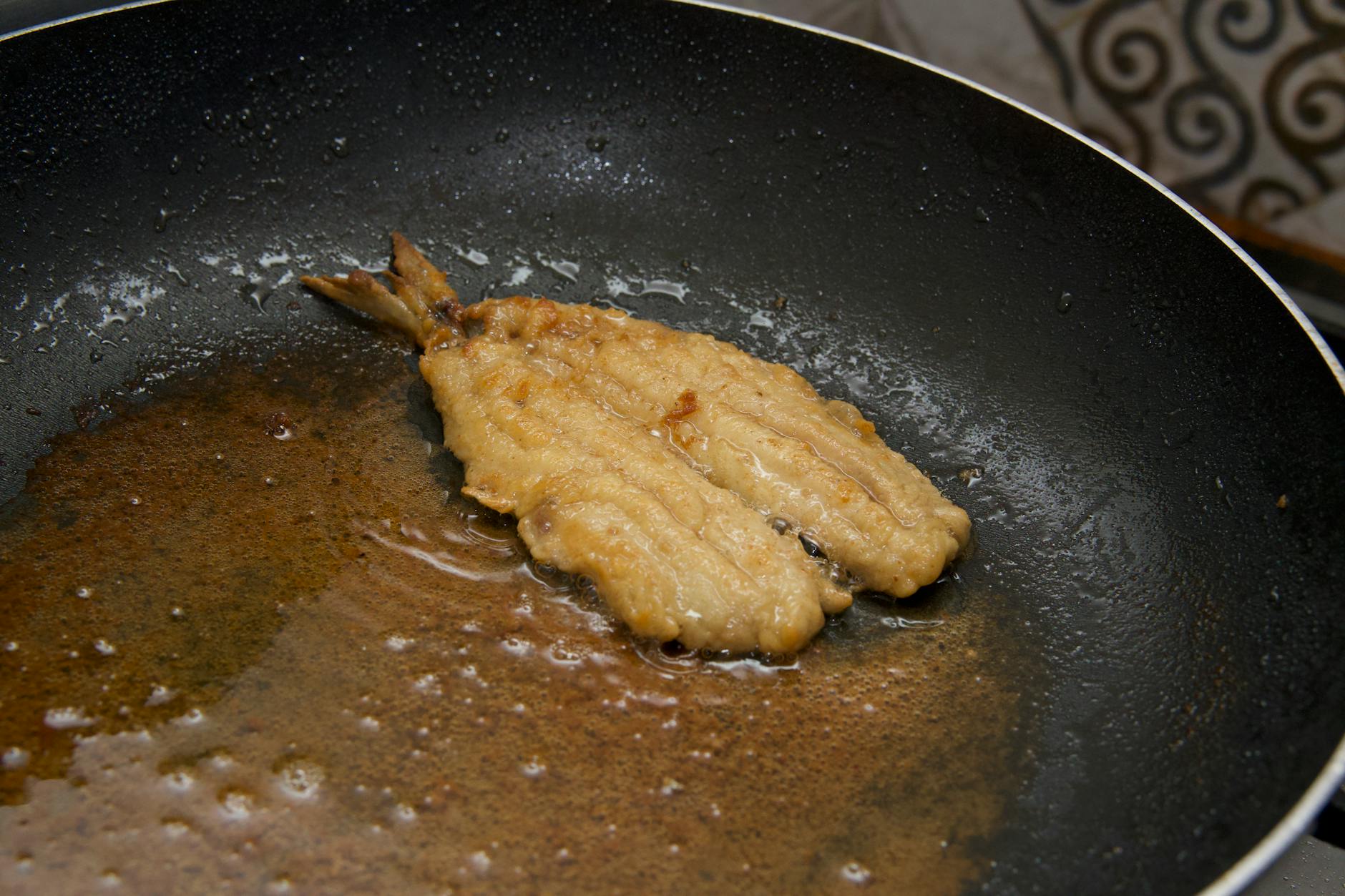 Delicate Flaky Fish Cooking In Nonstick Pan