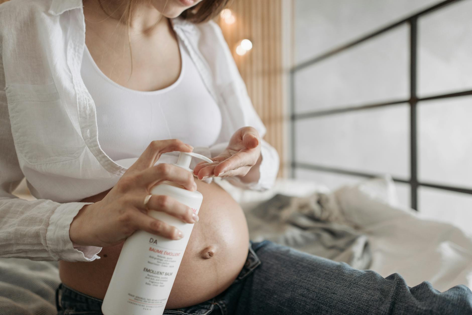 Pregnant Woman Applying Moisturizer To Belly