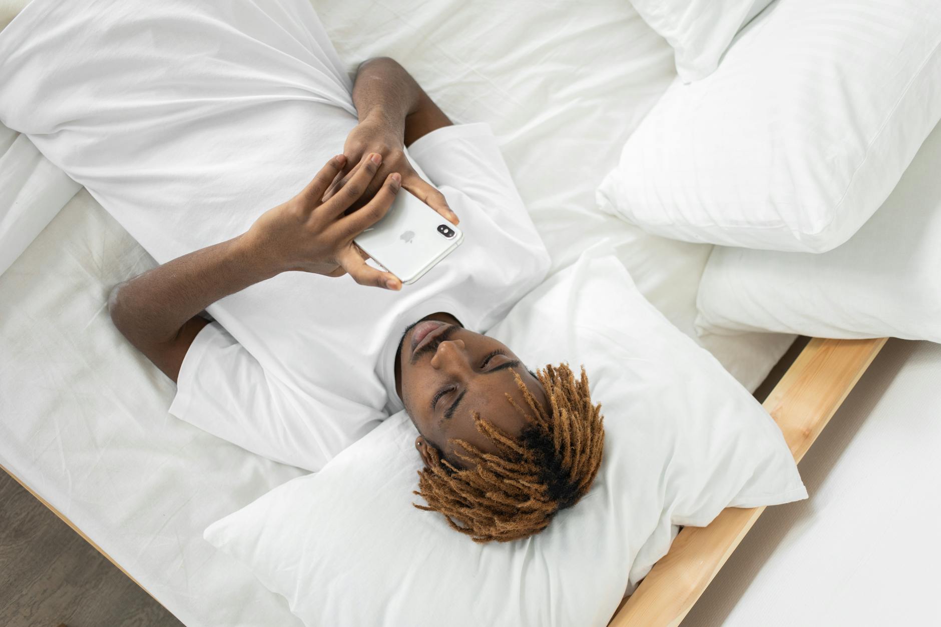 man looking at phone in bed